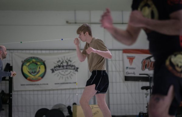 Ein junger Kämpfer übt Boxbewegungen in einem Trainingsraum.